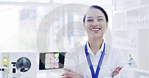 Happy, smiling and confident young female scientist standing alone in an empty modern laboratory with arms crossed