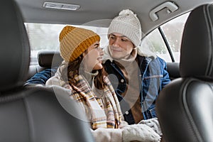 happy smiling couple on car back seat in winter