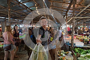 Happy Smiling Couple Hold Bags With Vegetables In Street Market Cheerful Man And Woman Shopping Together On Exotic