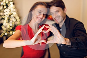 Happy smiling couple making heart shape with hands,