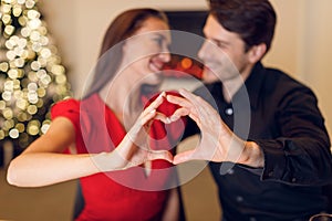 Happy smiling couple making heart shape with hands