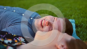 Happy Smiling Couple Relaxing on Green Grass. Male in focus