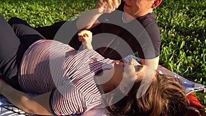 Happy smiling couple relaxing on green grass. Park.Young family lying on grass outdoors.