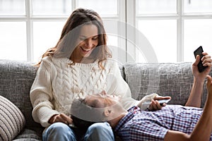 Happy smiling couple relaxing on sofa talking laughing holding