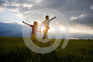 Happy smiling couple run on the field