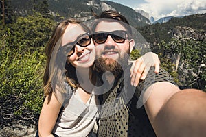 Happy smiling couple of students in love take selfie self-portrait while hiking in Yosemite National Park, California