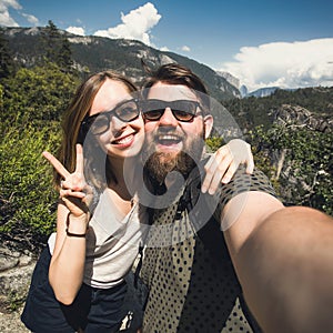 Happy smiling couple of students in love take selfie self-portrait while hiking in Yosemite National Park, California