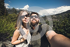 Happy smiling couple of students in love take selfie self-portrait while hiking in Yosemite National Park, California