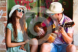 Happy smiling couple in sunglass and hat with guitar drinking j