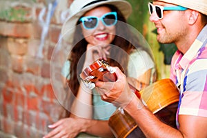 Happy smiling couple in sunglass and hat with guitar drinking j