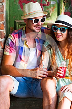 Happy smiling couple in sunglass and hat with guitar drinking j