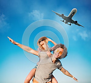 Happy smiling couples playing at the beach with aircraft in the sky