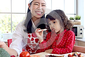 Happy smiling cute little girl eating chocolate and face covered in chocolate, adorable child daughter enjoy spending time