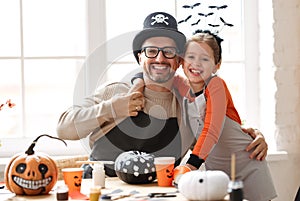 Happy smiling dad and daughter in Halloween hats smiling at camera while preparing home decorations