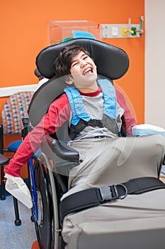 Happy, smiling disabled boy in wheelchair waiting in doctor's of