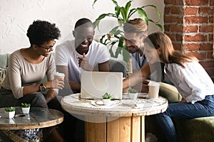 Happy smiling diverse friends using laptop together in cafe