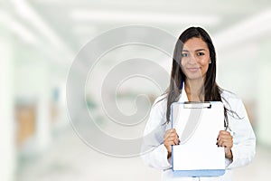 Happy smiling doctor holding clipboard standing in hospital hallway