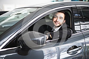 Happy smiling driver in the car, portrait of young successful business man