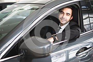 Happy smiling driver in the car, portrait of young successful business man