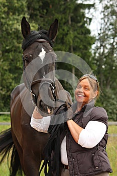 Happy smiling elderly woman and black horse portrait