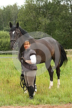 Happy smiling elderly woman and black horse portrait