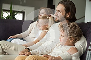 Happy smiling family with children sitting on sofa watching tv