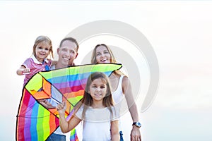 Happy smiling family with flying a kite on the beach