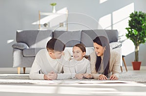 Happy smiling family hugging while lying on the floor in the room at home. C