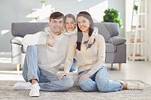 Happy smiling family hugging sitting on floor in room at home.