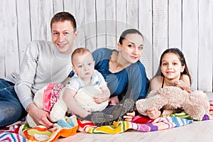 Happy smiling family lie with toys on colorful blanket on the floor and look on camera