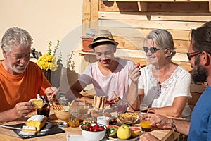 Happy smiling family multi generation at breakfast. Wooden table on the terrace under the sun. Fresh fruit and sweet food to start