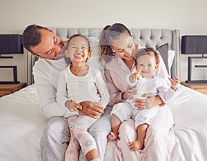 Happy, smiling and a family in pajamas on bed with small girls. Young mother and father with girl children in bedroom in