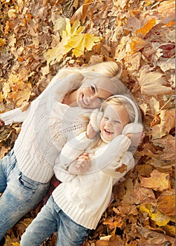 Happy smiling family portrait, mother and daughter have a rest laying on maple leaves