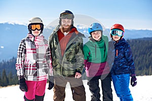 Happy smiling family on skis and snowboard in deep snow on background of winter mountains.