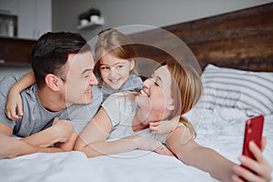 Happy smiling family take selfie on bed