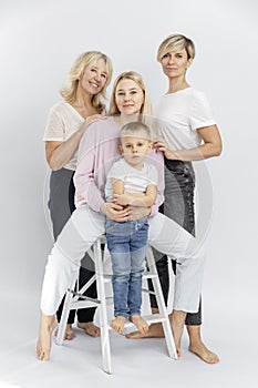 Happy smiling family. Three generations of women and a little boy in white T-shirts and jeans. Full height. Love and tenderness.