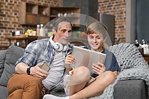 Happy Smiling Father And Son Sitting On Couch Use Tablet Computer, Parent Spending Time Child