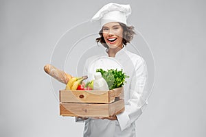 Happy smiling female chef with food in wooden box