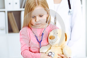 Happy smiling female kid-patient at usual medical inspection. Doctor and young girl in the clinic. Medicine, healthcare