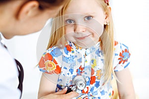 Happy smiling female kid-patient at usual medical inspection. Doctor and young girl in the clinic. Medicine, healthcare