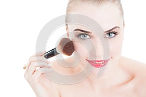 Happy smiling female model using make-up brush