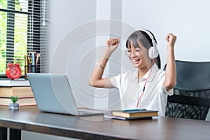 Happy smiling female student wearing headphones talking in online discussion meeting using laptop in home office. female college