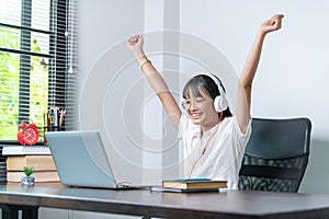 Happy smiling female student wearing headphones talking in online discussion meeting using laptop in home office. female college