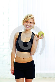 Happy smiling fit woman holding green apple