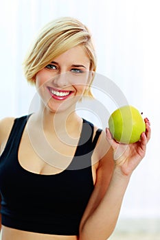 Happy smiling fit woman holding green apple