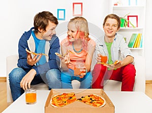 Happy smiling friends eat together pizza at home