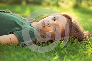 Happy smiling fun casual kid girl lying on the grass on nature summer background. Closeup