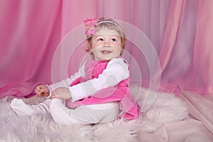 Happy smiling funny little girl resting on bed over pink draper