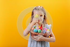 A happy smiling girl with a basket full of colored eggs.