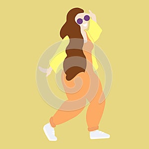 Happy smiling girl with brown long hair dressed in trendy clothes. Dancing young lady in purple round sunglasses isolated on